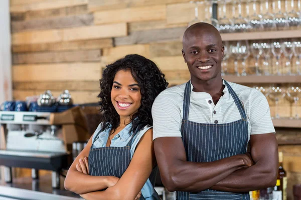 Porträt eines lächelnden Kellners und einer Kellnerin, die Rücken an Rücken am Schalter stehen — Stockfoto