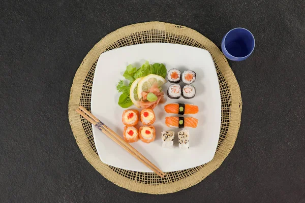 Conjunto de sushi sortido servido com pauzinhos e vidro no tapete de sushi — Fotografia de Stock