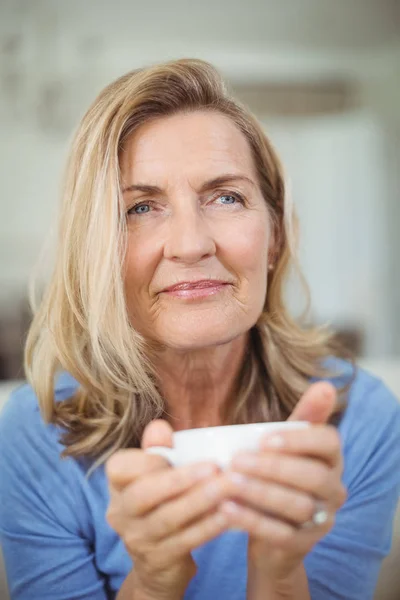 Mujer mayor reflexiva tomando una taza de café en la sala de estar — Foto de Stock