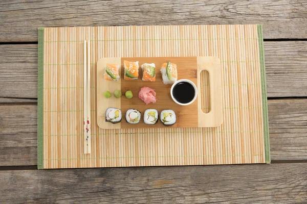 Bricka med blandade sushi höll på matta — Stockfoto