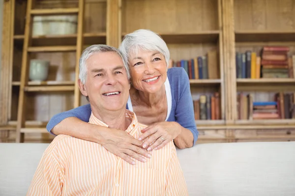 Lächelnde Seniorin umarmt Mann im Wohnzimmer — Stockfoto