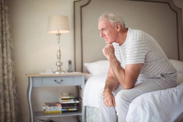 Nadenkende man zit op bed in de slaapkamer — Stockfoto