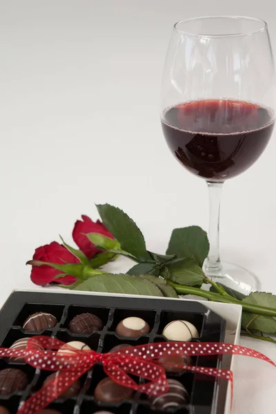 Bunch of roses, wine glass and assorted chocolate box — Stock Photo, Image