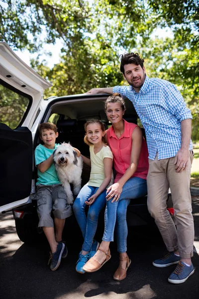 Família feliz sentado no porta-malas do carro com seu cão — Fotografia de Stock