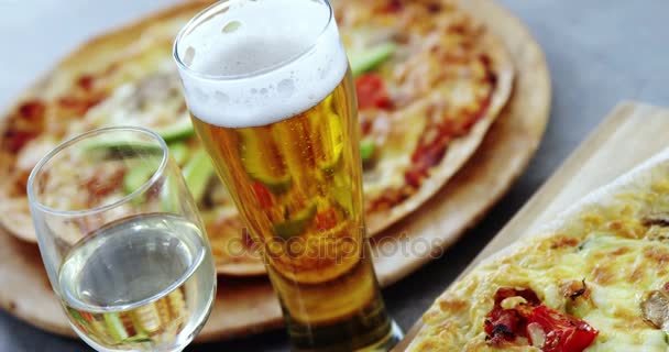 Deliciosa pizza con copas de cerveza y vino — Vídeos de Stock