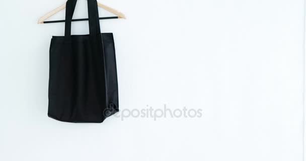 Handbag and hanger hanging on white wall — Stock Video