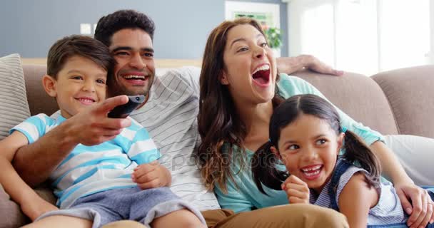 Família sentada no sofá e assistindo televisão — Vídeo de Stock