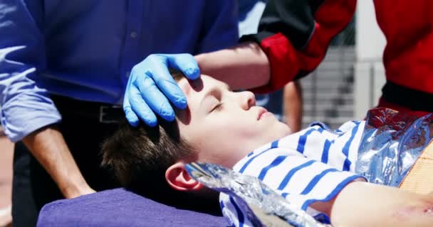 Paramedics examining injured boy — Stock Video