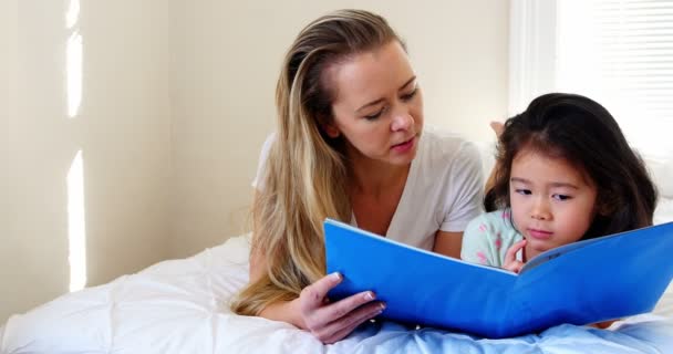 Moeder en dochter leesboek op bed — Stockvideo