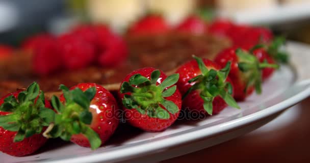 Bord met aardbeien en dessert op teller — Stockvideo