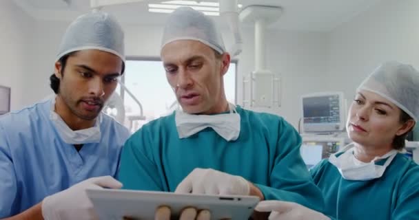 Хирурги обсуждают за планшетом — стоковое видео