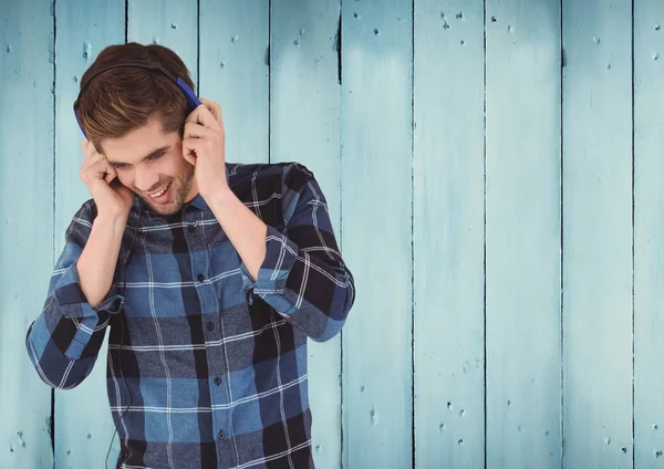 Mann med hodetelefoner mot trepanel – stockfoto