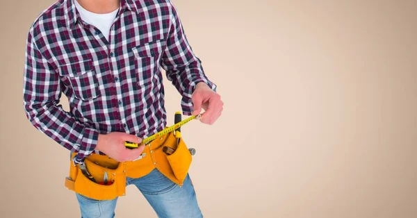 Carpenter with measuring tape against cream background — Stock Photo, Image