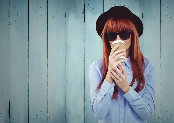 Woman with coffee and hat against blue wood panel — Stock Photo, Image