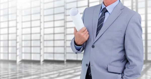 Arquitecto Torso sosteniendo planos en un pasillo contra ventanas — Foto de Stock