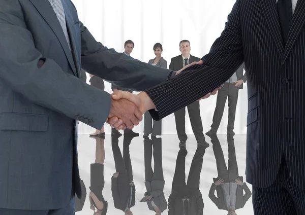 Handshake in front of business people at window — Stock Photo, Image