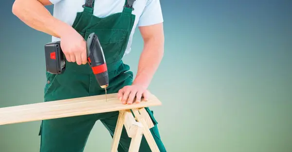 Composite image of Carpenter drilling against blue green background — Stock Photo, Image