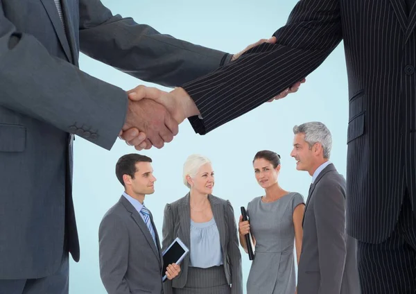 Händedruck vor Geschäftsleuten vor blauem Hintergrund — Stockfoto