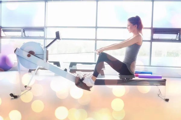 Mujer haciendo ejercicio en la máquina de fila — Foto de Stock