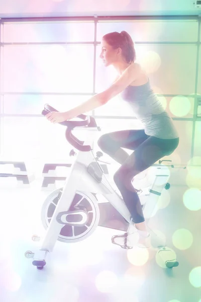 Woman energetically riding exercise bike — Stock Photo, Image