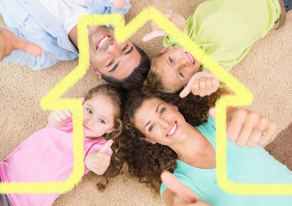 Família deitado no tapete em casa contra o contorno da casa no fundo — Fotografia de Stock