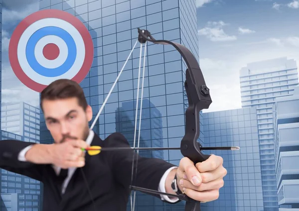 Businessman aiming at target with bow and arrow — Stock Photo, Image