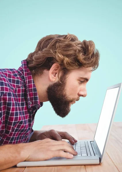 Uomo barbuto guardando vicino al computer portatile alla scrivania — Foto Stock