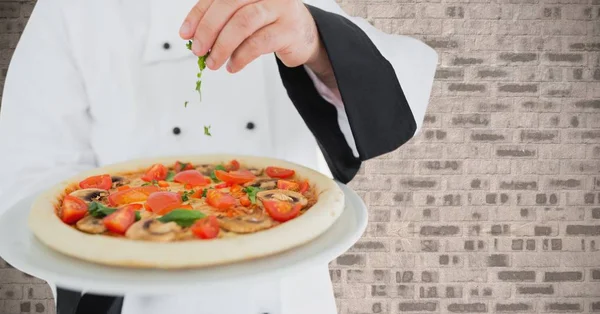 Chef sprinkling herbs on pizza — Stock Photo, Image