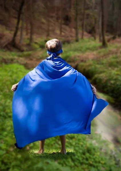 Kid in blue cape standing in field — Stock Photo, Image