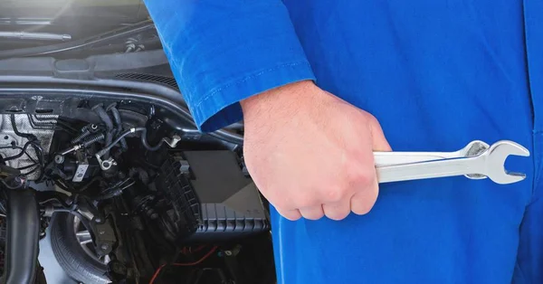 Mechanic holding wrench in garage — Stock Photo, Image