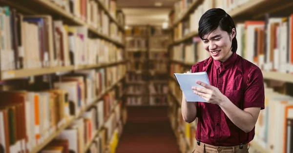 Homem escrevendo no bloco de notas na biblioteca — Fotografia de Stock