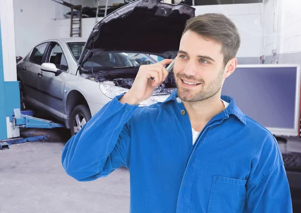 Mecânico de automóveis usando telefone celular na oficina — Fotografia de Stock