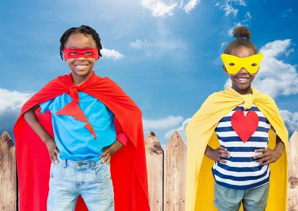 Niños en traje de superhéroe con las manos en la cintura de pie contra el cielo en el fondo —  Fotos de Stock