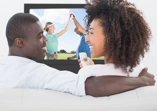 Pareja sonriendo mientras ve golf en la televisión — Foto de Stock