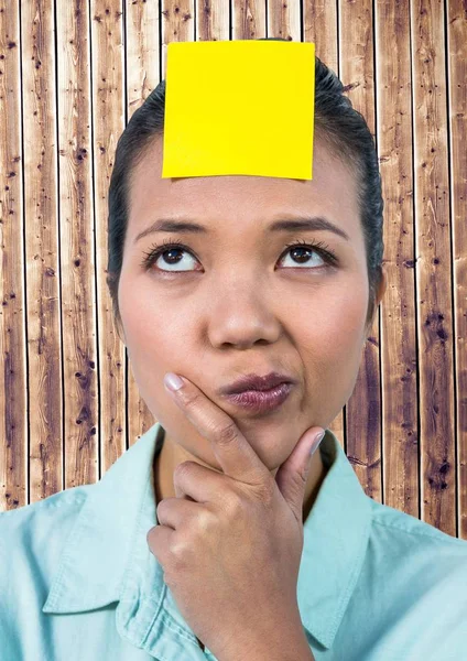 Gefrustreerd vrouw met sticky note geplakt op haar voorhoofd tegen houten achtergrond — Stockfoto