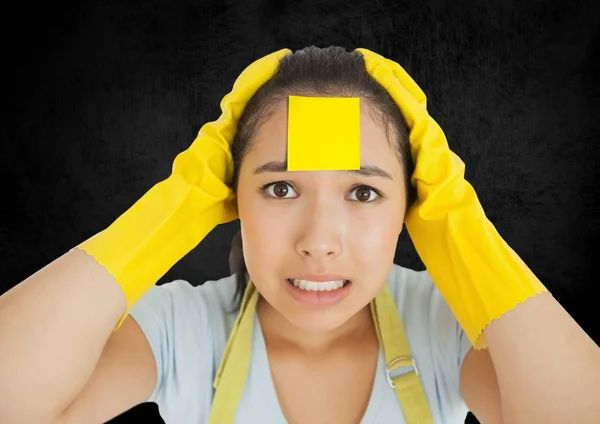 Reiniger met sticky note vast o haar gezicht tegen zwarte achtergrond — Stockfoto