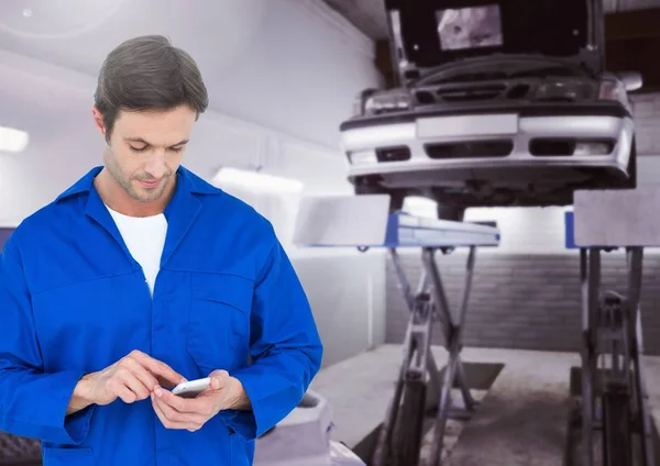 Meccanico utilizzando il telefono cellulare in garage — Foto Stock