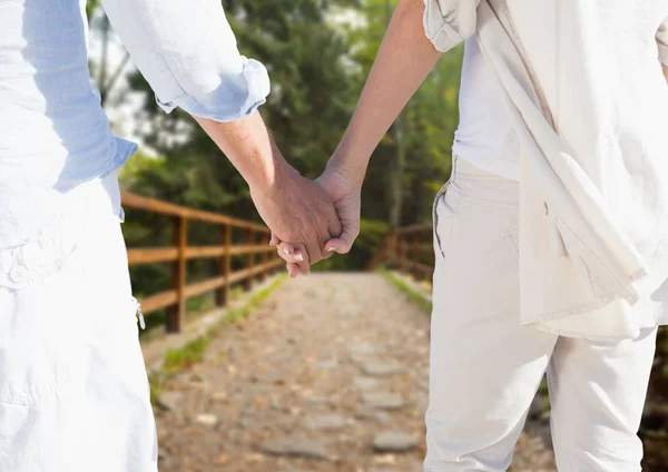 Mid section of couple holding hands walking on footbridge — Stock Photo, Image