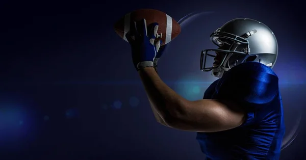 American football player catching a ball against blue background Stock Photo