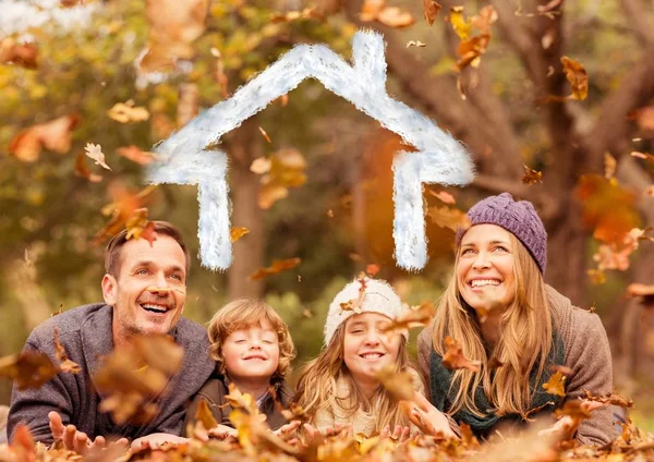 Familia superpuesta con forma de casa acostada sobre hojas secas en el parque —  Fotos de Stock