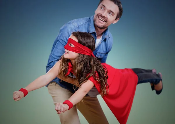 Papà portando sua figlia in costume da supereroe sullo sfondo verde — Foto Stock
