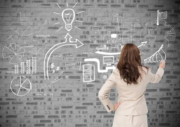 Rear view of businesswoman drawing icons on brick wall — Stock Photo, Image