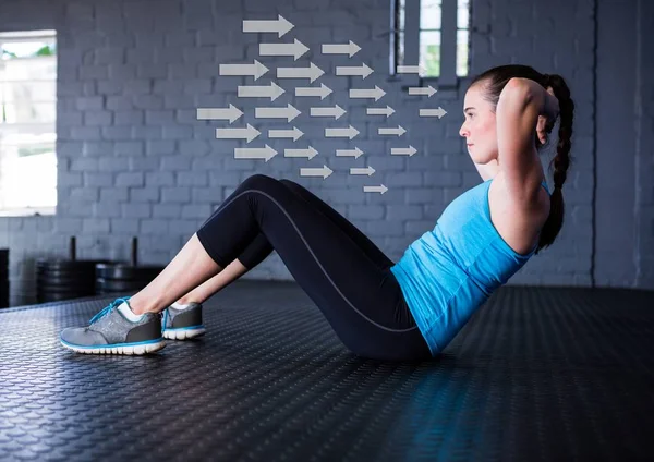 合适的女人在健身房反方向箭头在背景中执行仰卧起坐锻炼 — 图库照片