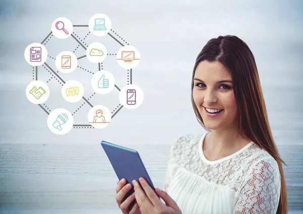 Frau benutzt digitales Tablet gegen Anwendungssymbole im Hintergrund — Stockfoto