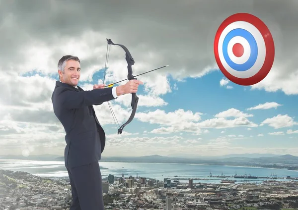 Retrato de empresário apontando com arco e flecha para o alvo sobre a paisagem urbana — Fotografia de Stock