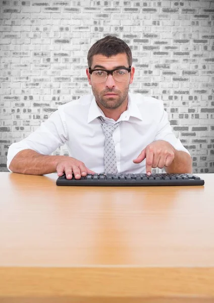 Homem em óculos digitando no teclado contra o fundo da parede de tijolo — Fotografia de Stock