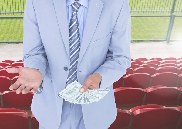 Corrupt businessman holding money in stadium — Stock Photo, Image
