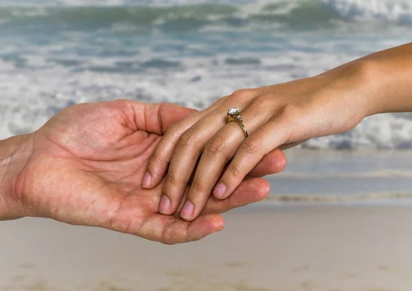 Frischvermähltes Paar hält Händchen am Strand — Stockfoto