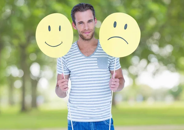 man holding happy and sad smiley faces