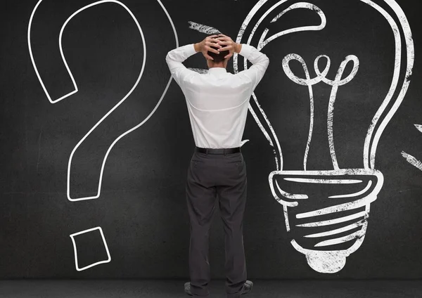 Stressed man standing against question mark and bulb drawn on wooden background — Stock Photo, Image